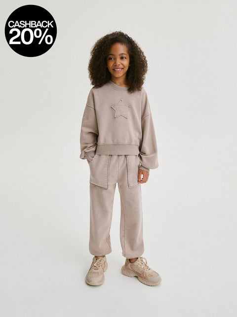 Child wearing a beige tracksuit on a white background