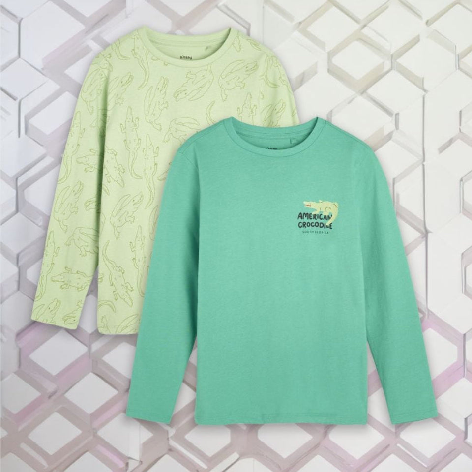Two long-sleeve crewneck shirts displayed flat against a geometric white and pink background. The front shirt is mint green with a small 'APECK CROCODILE' graphic on the left chest, and the back shirt is pale yellow-green with a subtle reptile pattern.