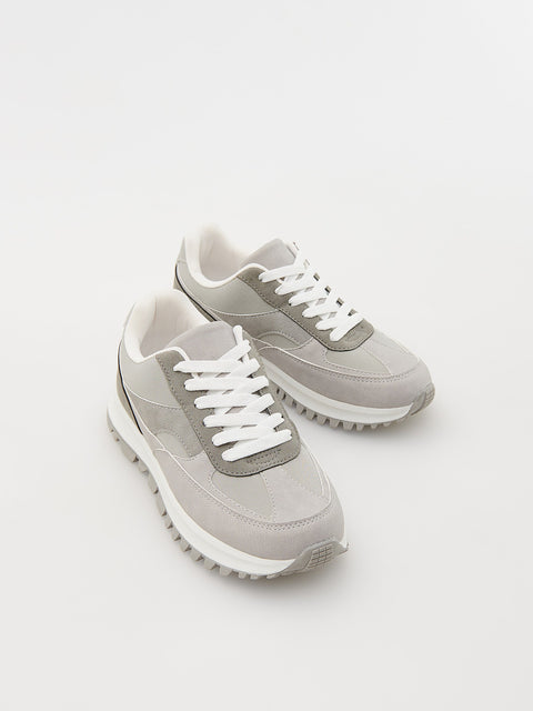 Pair of gray sneakers with white soles on a light gray background