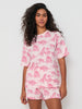 Woman wearing a pink and white pajama set with animal pattern on a white background