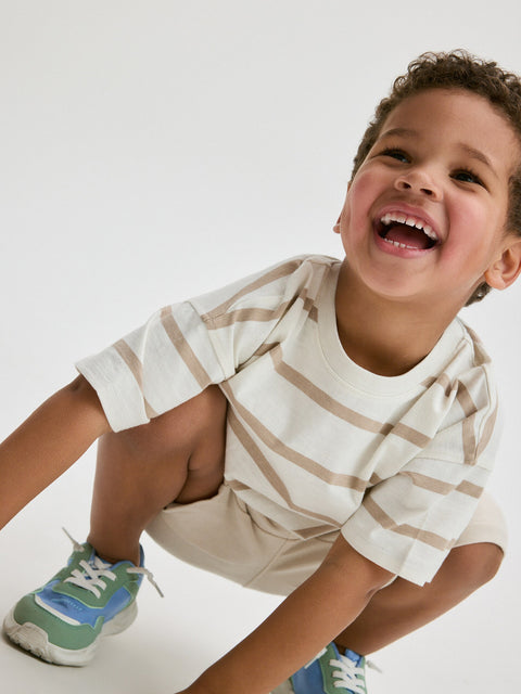 Child wearing a striped shirt and sneakers on a white background
