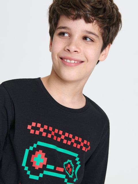 Young boy wearing a black sweater with a pixelated design on a light gray background
