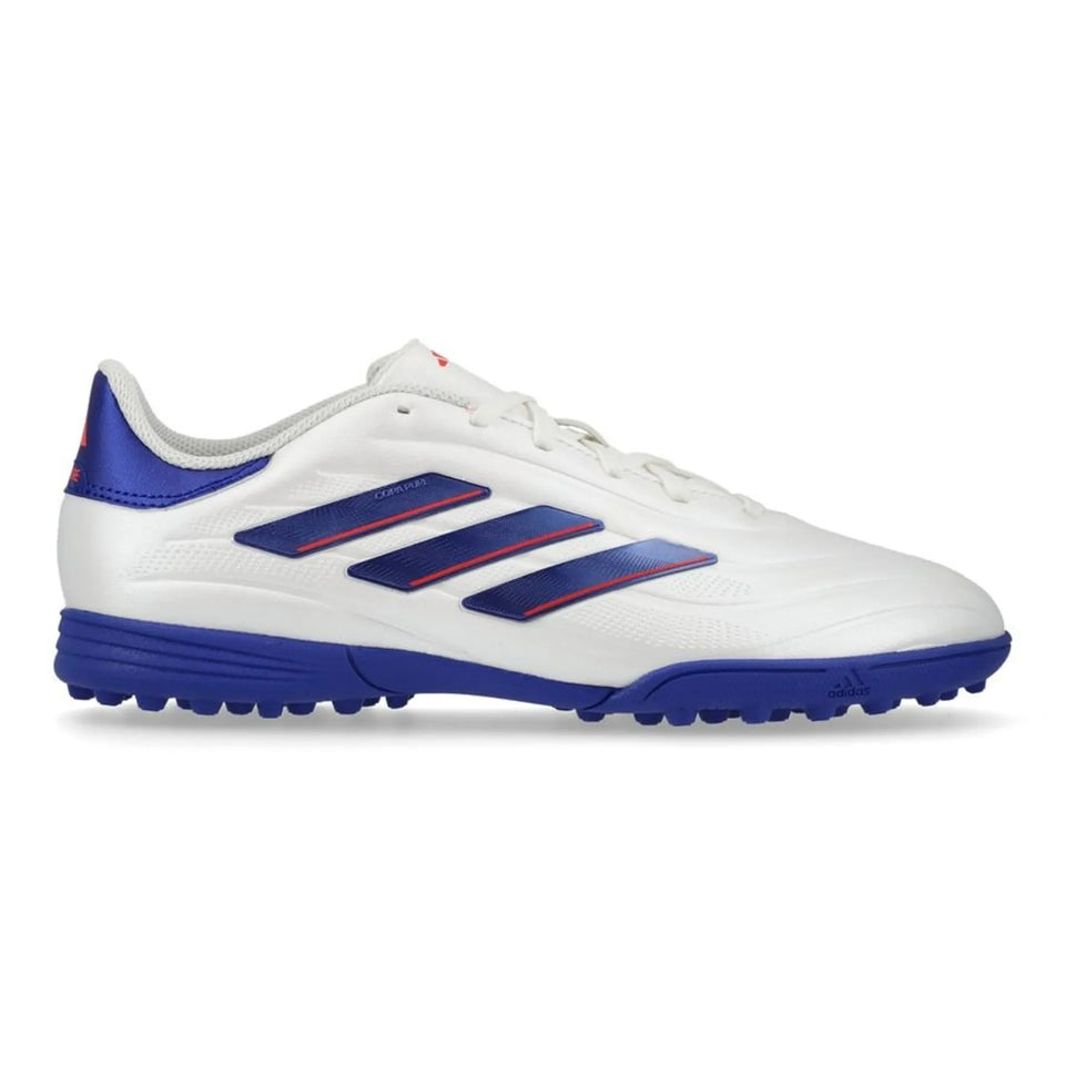 A white Adidas soccer turf shoe with royal blue stripes and sole, accented by thin red lines along the stripes.