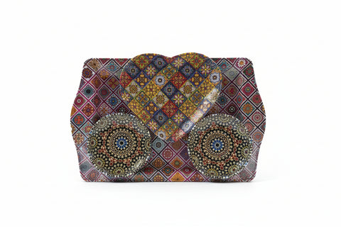 Decorative phone case with intricate patterns held by a hand on a textured surface.