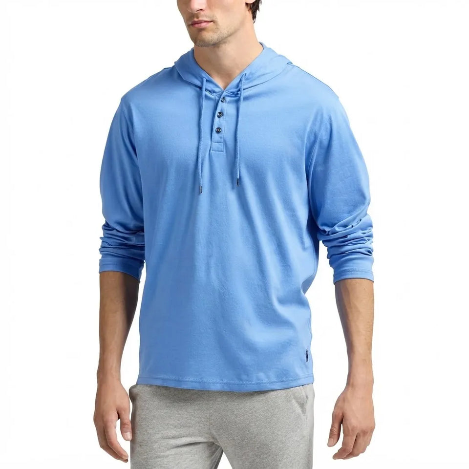 A man wearing a light blue long-sleeve hooded henley shirt with gray sweatpants, shown from the waist up against a plain white background.