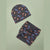 A dark gray fabric beanie and matching headband with an allover print of blue cars and orange flames, laid flat on a light sage green background.