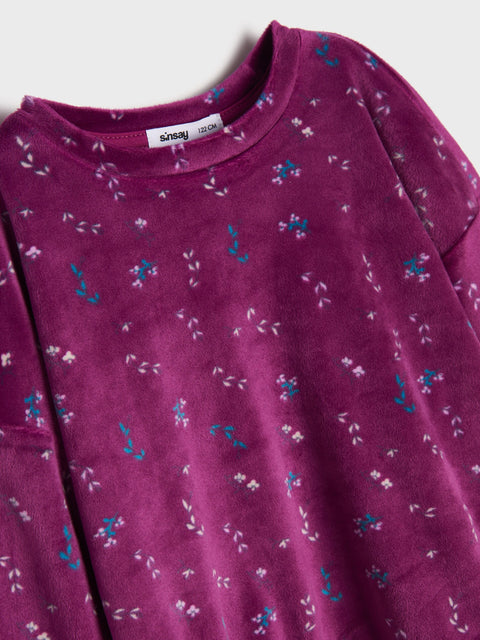 Close-up of a purple garment with floral pattern on a plain background