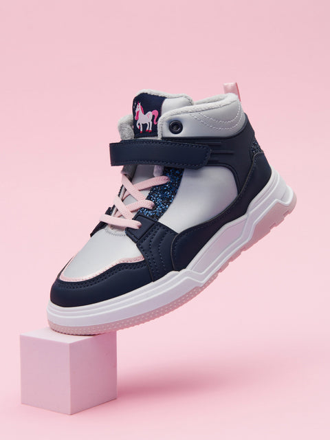 Navy and white sneaker with pink accents on a pink block against a pink background