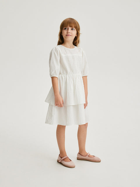 Young girl wearing a white dress on a plain background