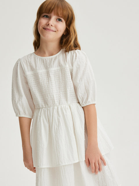 Young girl wearing a white dress against a plain background