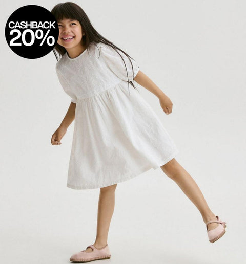 Young girl in a white dress standing on a plain background