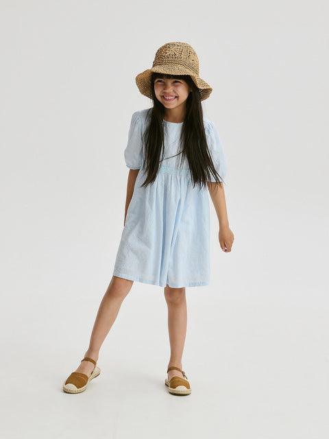 Young girl wearing a light blue dress and straw hat on a white background