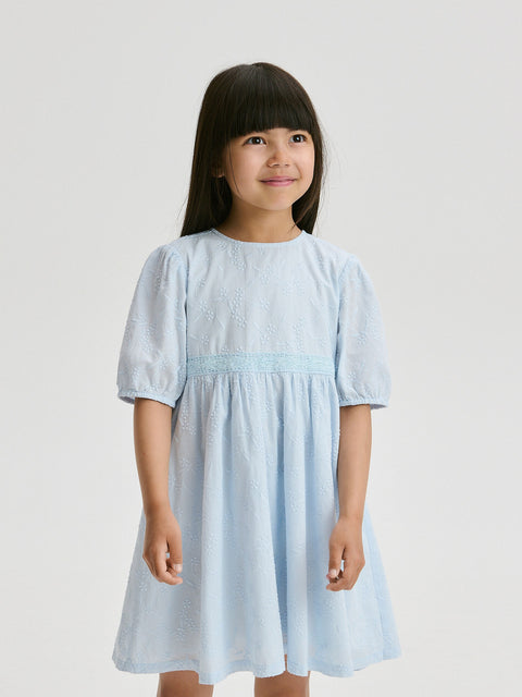 Young girl wearing a light blue dress against a plain background