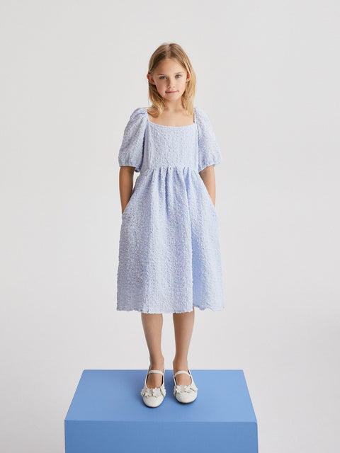 Young girl wearing a light blue dress on a white background