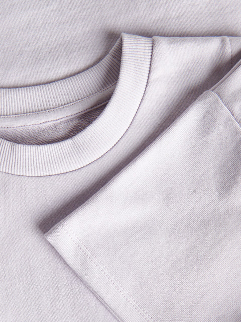 Close-up of a light gray sweatshirt with a focus on the collar and sleeve.