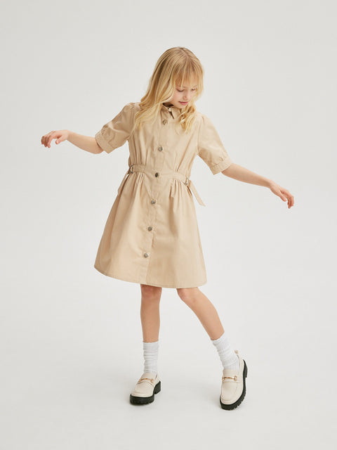 Young girl wearing a beige trench coat on a white background