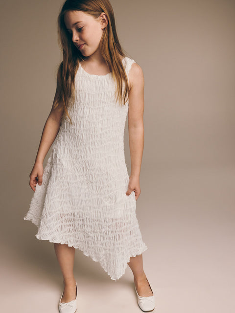 Young girl wearing a white dress against a plain background