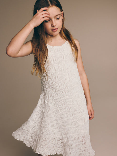 Young girl wearing a white dress against a beige background