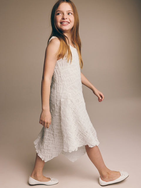 Young girl wearing a white dress against a beige background