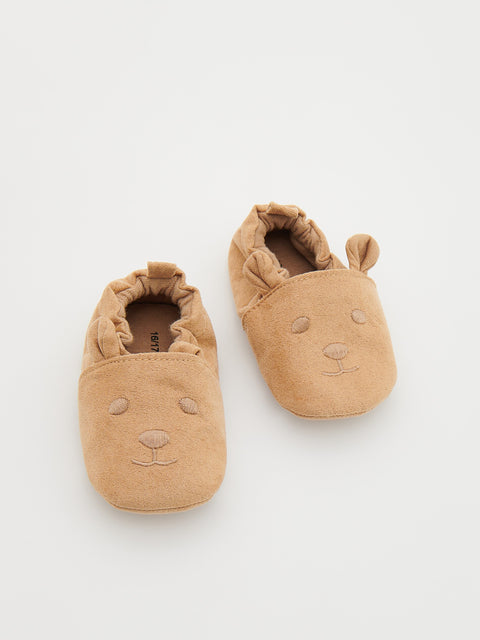 Pair of tan baby shoes with bear face design on a white background