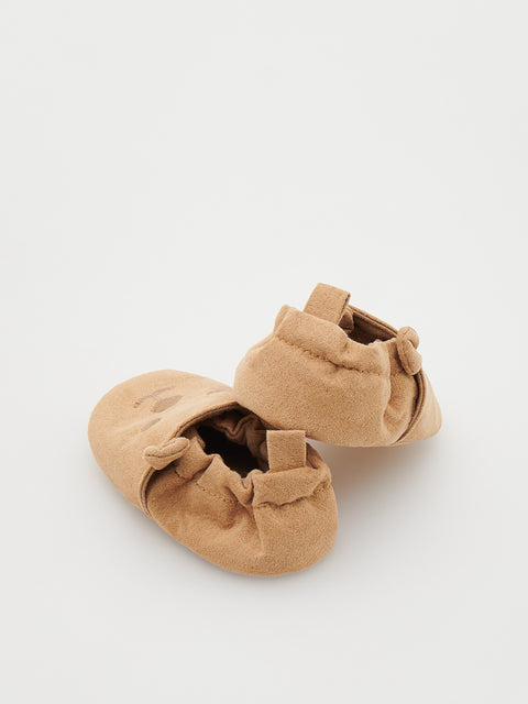 Pair of tan baby shoes on a white background