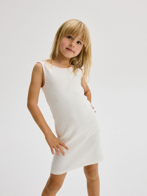 Young girl wearing a white dress against a plain background