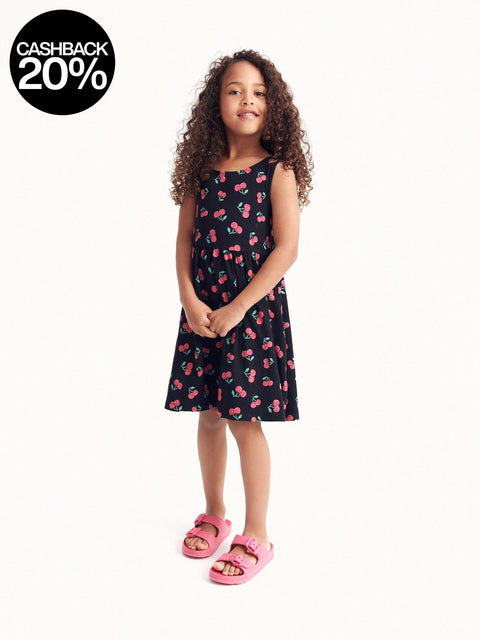 Young girl wearing a black dress with pink cherry pattern on a white background