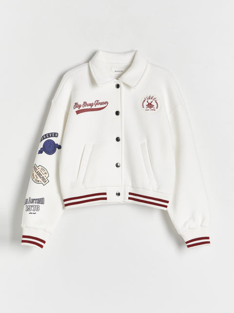 White varsity jacket with embroidered logos on a light gray background