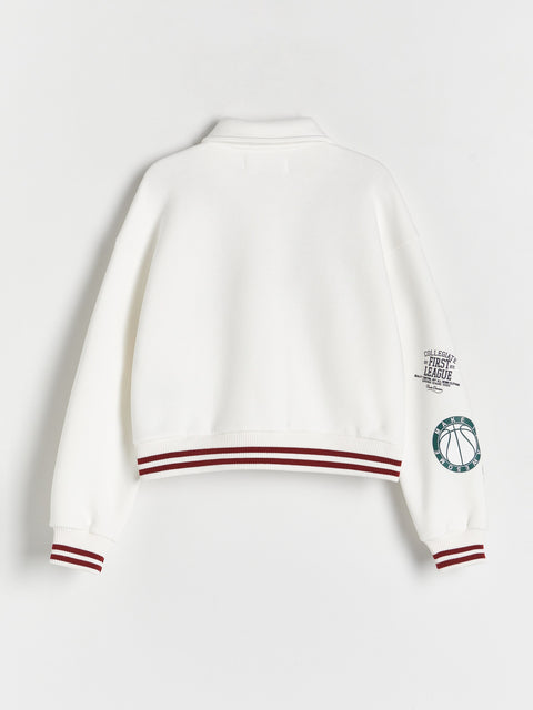 White sweater with red accents and a logo on a light gray background