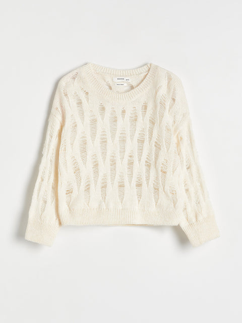 Cream-colored cable knit sweater on a light gray background