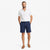 A man modeling a white short-sleeve button-down shirt and navy blue shorts against a clean white background.