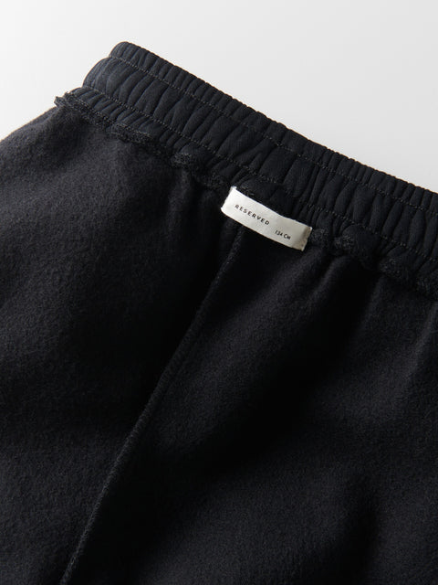 Black pants with a brand label on the waistband against a light gray background