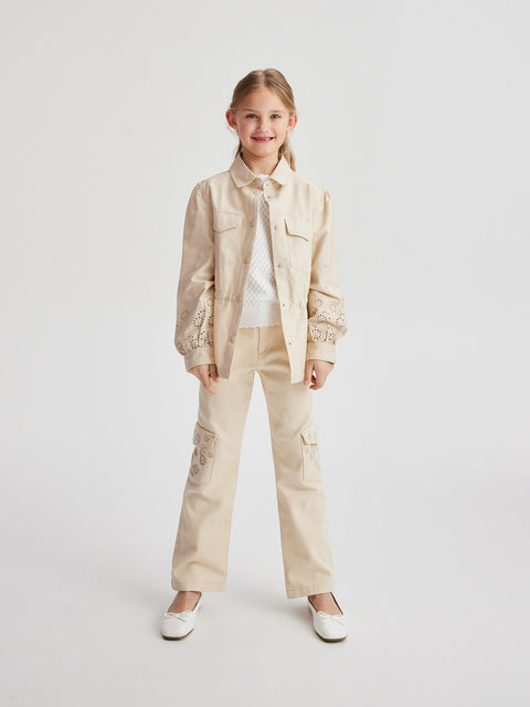 Young girl wearing a beige jacket and pants on a white background