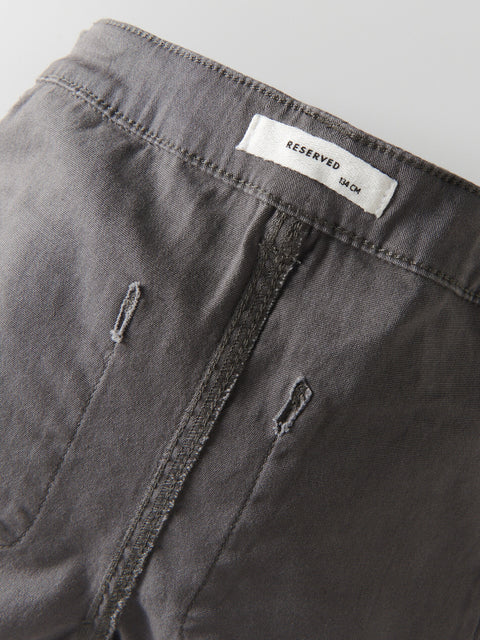 Close-up of a gray pants with a 'RESERVED' label on a gray background