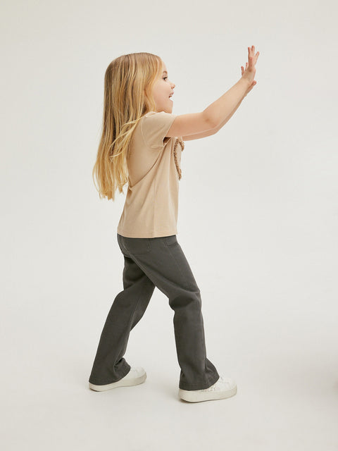 Child wearing a beige shirt and gray pants on a white background