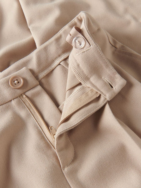 Close-up of beige fabric with buttons and a zipper