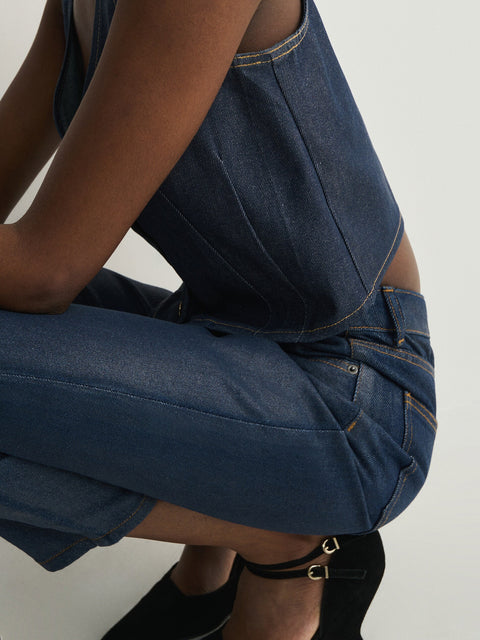 Person wearing a blue denim dress with a plain background