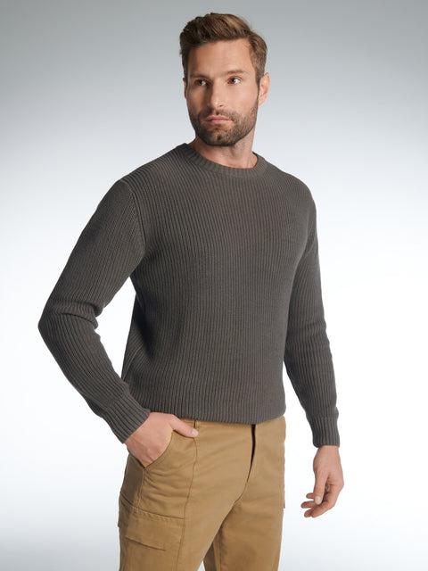 Man wearing a gray sweater and beige pants against a light gray background