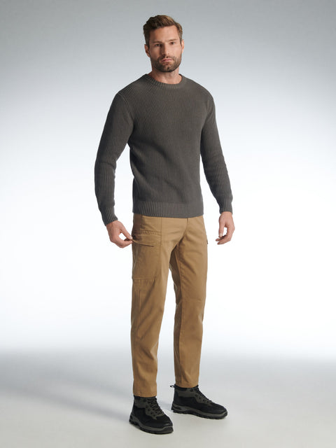 Man wearing a gray sweater and tan pants on a white background