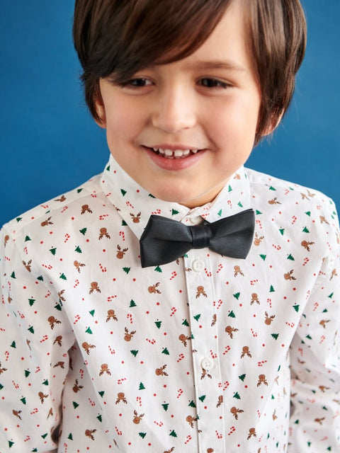 Child wearing a patterned shirt with a bow tie against a blue background