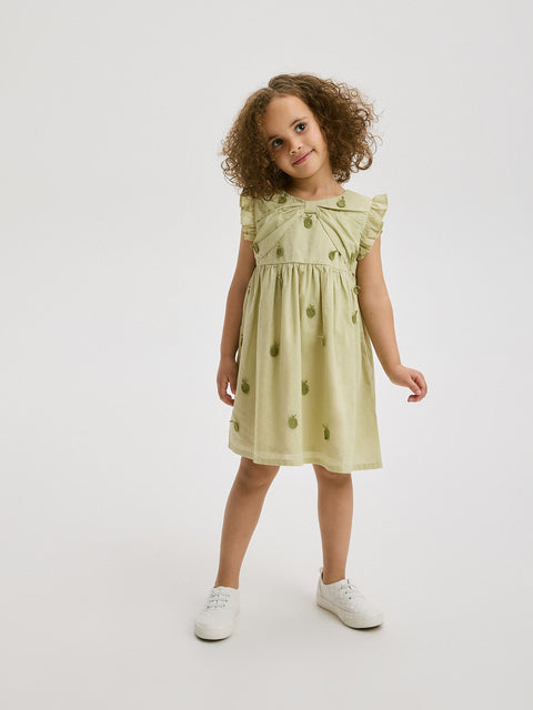 Young girl wearing a light green dress with a white background
