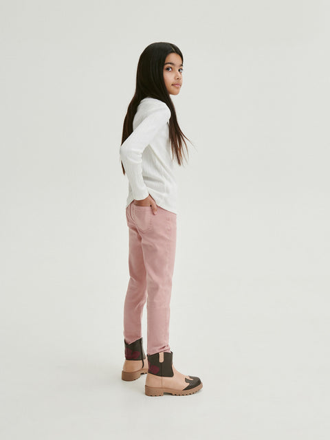 Person wearing a white sweater and pink pants on a light gray background