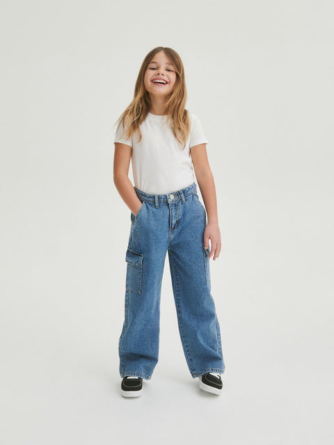 Person wearing a white t-shirt and blue jeans on a plain background