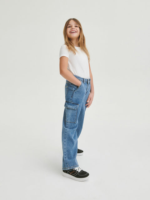 Person wearing blue jeans and a white shirt on a light gray background