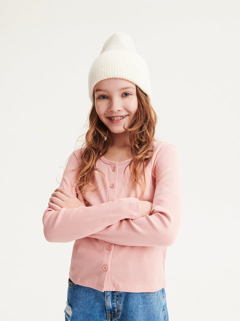 Young girl wearing a pink cardigan and white beanie on a light background
