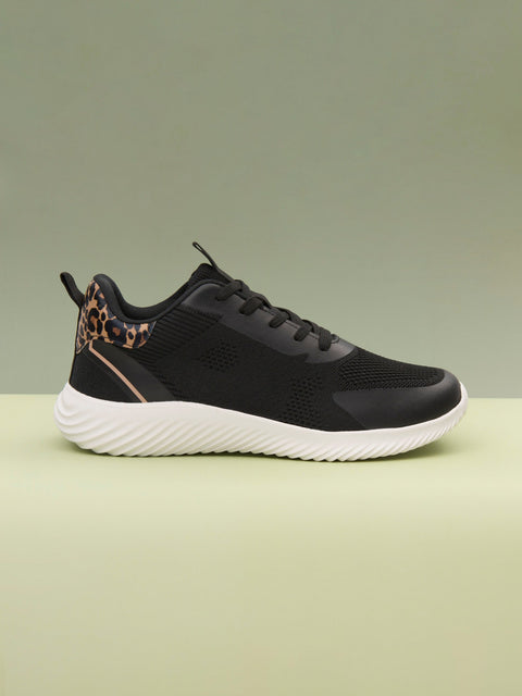 Black sneaker with leopard print accents on a light green background