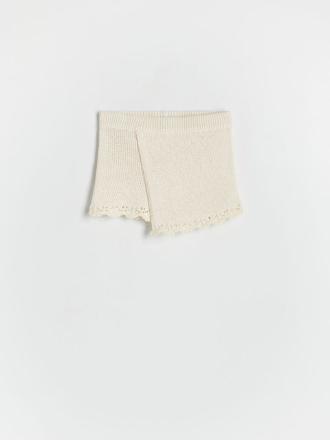 Folded beige knitted blanket on a white background