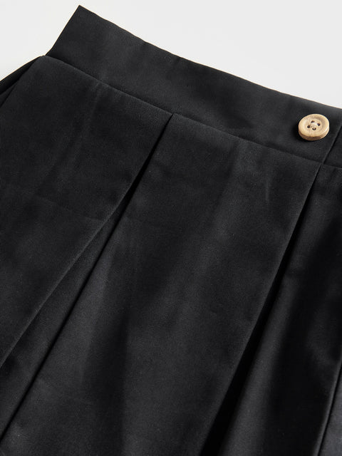 Close-up of black pants with a button on a light gray background