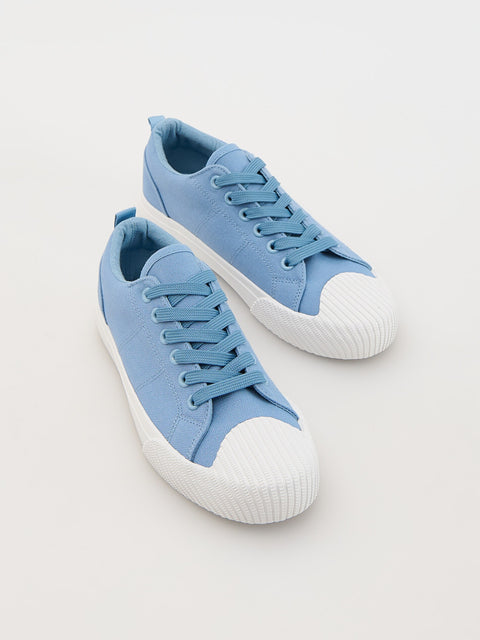 Pair of light blue sneakers with white soles on a light gray background