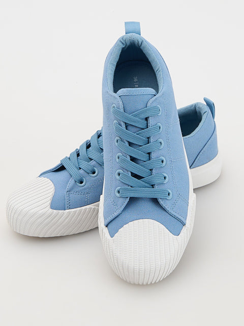 Pair of blue sneakers with white soles on a light gray background